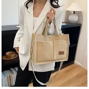 Gros plan du sac fourre-tout en toile beige avec doubles poches et étiquette en cuir marron