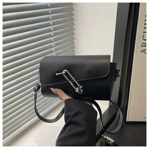 Détail du sac bandoulière en similicuir noir avec une grande boucle métallique argentée