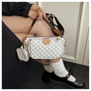 Detail of white crossbody bag with dark M-pattern print and adjustable wide fabric strap