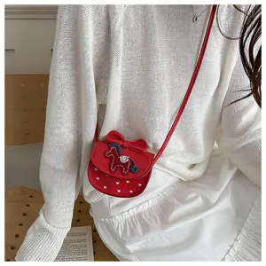Détail du sac bandoulière rouge pour fille avec poney brodé et nœud en décor de style de vie