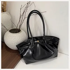 Dettaglio borsa sottobraccio nera lucida con design arricciato e fibbia dorata