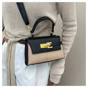 Détail d'un sac bicolore en paille avec poignée en cuir noir et fermoir doré chic