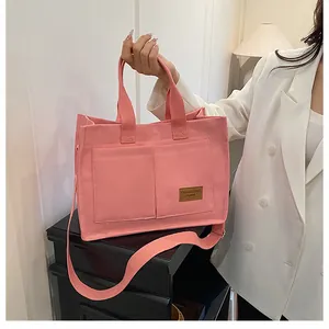 Détail de sac cabas en toile rose avec poches avant et étiquette de marque en cuir