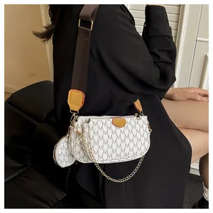 Close-up of beige crossbody bag with M-pattern print, chain strap, and mini coin purse