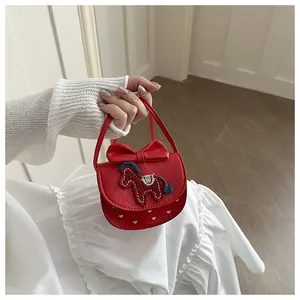 Détail d'un mini sac rouge matelassé avec nœud, broderie de cheval et motifs de cœur
