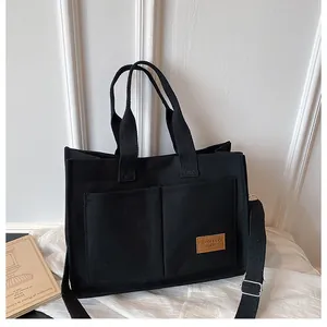Détail du sac cabas en toile noire avec poches avant et bandoulière réglable