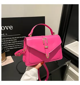 Detail of fuchsia leather handbag with gold U-shaped buckle and envelope flap