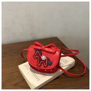 Détail du mini sac rouge matelassé en cuir PU avec nœud et broderie poney sur un livre