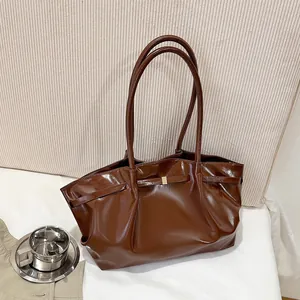 Borsa tote marrone scuro lucida con fibbia dorata in un interno accogliente