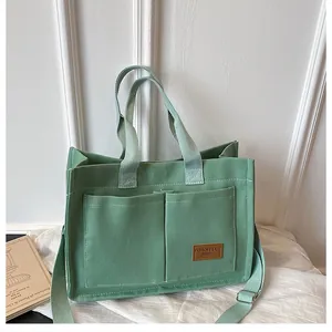 Vue détaillée du sac en toile vert menthe avec étiquette en cuir brun et sangle ajustable