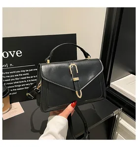 Close-up of a black faux leather bag with gold U-shaped buckle and a minimalist coffee cup
