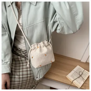 Detail of cream knitted bucket bag with orange daisy embroidery and drawstring tassels