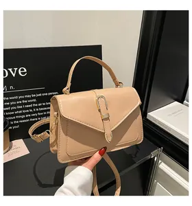 Detail of beige handbag with elegant V-shaped flap and gold U-shaped metal buckle