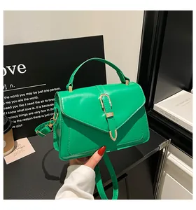 Detail of bright green envelope bag with a golden horseshoe metal buckle and top handle