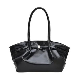 Borsa a spalla nera lucida con chiusura dorata e dettagli a pieghe su sfondo bianco