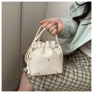 Close-up of knit bucket bag with daisy embroidery and drawstring closure detail