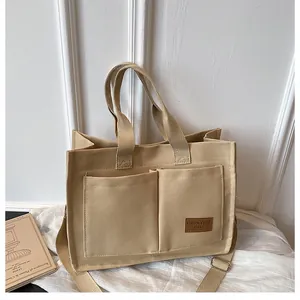 Gros plan sur un sac cabas en toile beige avec poches avant et bandoulière réglable