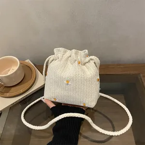 Minimalist knit bucket bag with yellow daisy embroidery and thick braided strap
