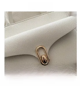 Close-up of white lychee texture leather with a polished gold oval metal twist lock