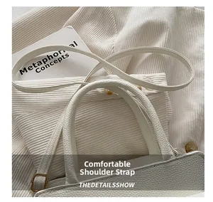 Detailed close-up of textured pebbled leather handle and strap on a white fashion handbag