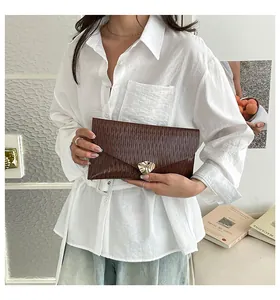 Detailansicht der dunkelbraunen Umschlag-Clutch mit Plissee-Struktur und Metallschnalle