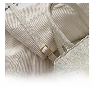 Detail shot of the adjustable metal buckle on a white lychee grain leather handbag