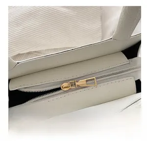 Macro shot of smooth gold zipper on white pebble leather bag with black lining