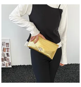 Detail der goldenen Briefumschlag-Clutch mit Wellenstruktur und silbernem Verschluss