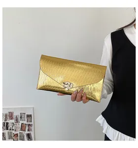 Detail der goldenen Briefumschlag-Clutch mit Wasserwellenstruktur und Metallschnalle