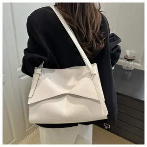 Detail of white geometric shoulder bag with a folding design shown on a model