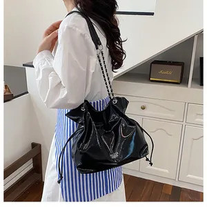 Détail du sac cabas noir brillant à cordon avec bandoulière chaîne et logo imprimé
