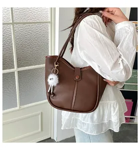 Brown vintage tote bag detail with long-legged plush doll pendant and magnetic buckle