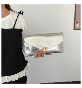Detailansicht der silbernen Clutch mit Wellenstruktur und goldenem Metallverschluss