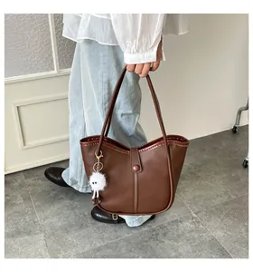 Detail showing deep brown faux leather tote bag with furry monster pendant on model