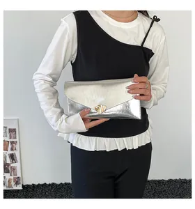 Detail der silbernen Umschlag-Clutch mit vertikaler Prägung und goldener Metallschließe