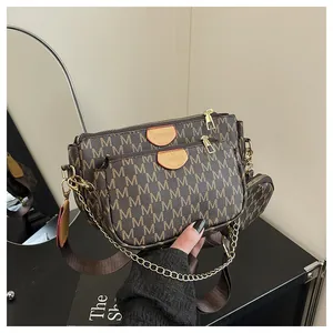 Close-up of brown monogram crossbody bag set with golden chains and wide nylon strap