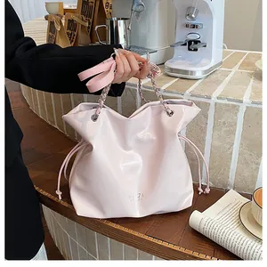 Détail du sac cabas rose brillant avec cordon de serrage et bandoulière en chaîne au café