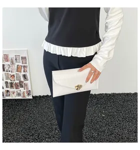 Detailansicht der weißen plissierten Umschlag-Clutch mit goldener Herzschnalle für Damen