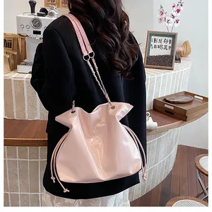 Détail d'un sac cabas en cuir verni rose avec fermeture à cordon et bandoulière chaîne