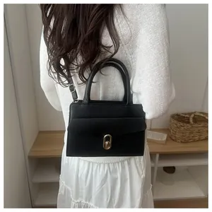 Detail shot of black litchi grain leather handbag with gold buckle and adjustable strap