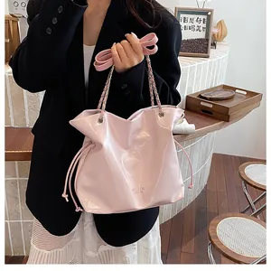 Détail du cabas en cuir verni rose avec cordons de serrage et bandoulière chaîne