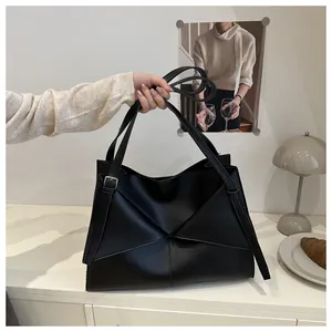 Close-up of matte black underarm bag with unique geometric folded leather patchwork