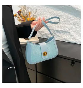 Detail of light blue woven texture and golden metal rotary buckle on the shoulder bag