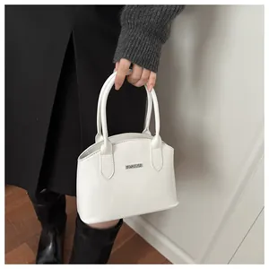 Close-up of white patent leather handbag with FASHION metal plate and glossy finish