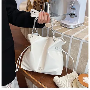 Détail d'un cabas blanc brillant avec chaîne argentée dans un décor de café