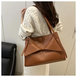Brown leather tote bag featuring foldable flap and silver adjustable buckles on straps