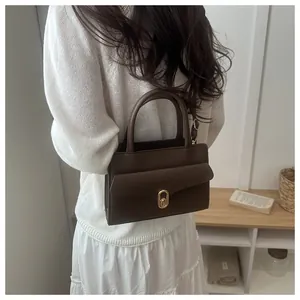 Close-up of coffee brown lychee leather bag with gold oval twist lock and strap