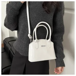 Close-up of a glossy white patent leather handbag with silver 'FASHION' metal plaque
