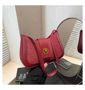 Detail of burgundy sequin underarm bag with golden rotary clasp and polished leather trim