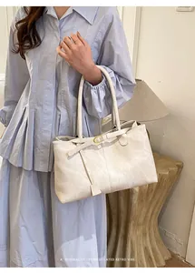 Detail of cream white faux leather tote bag with gold buckle and smooth retro texture